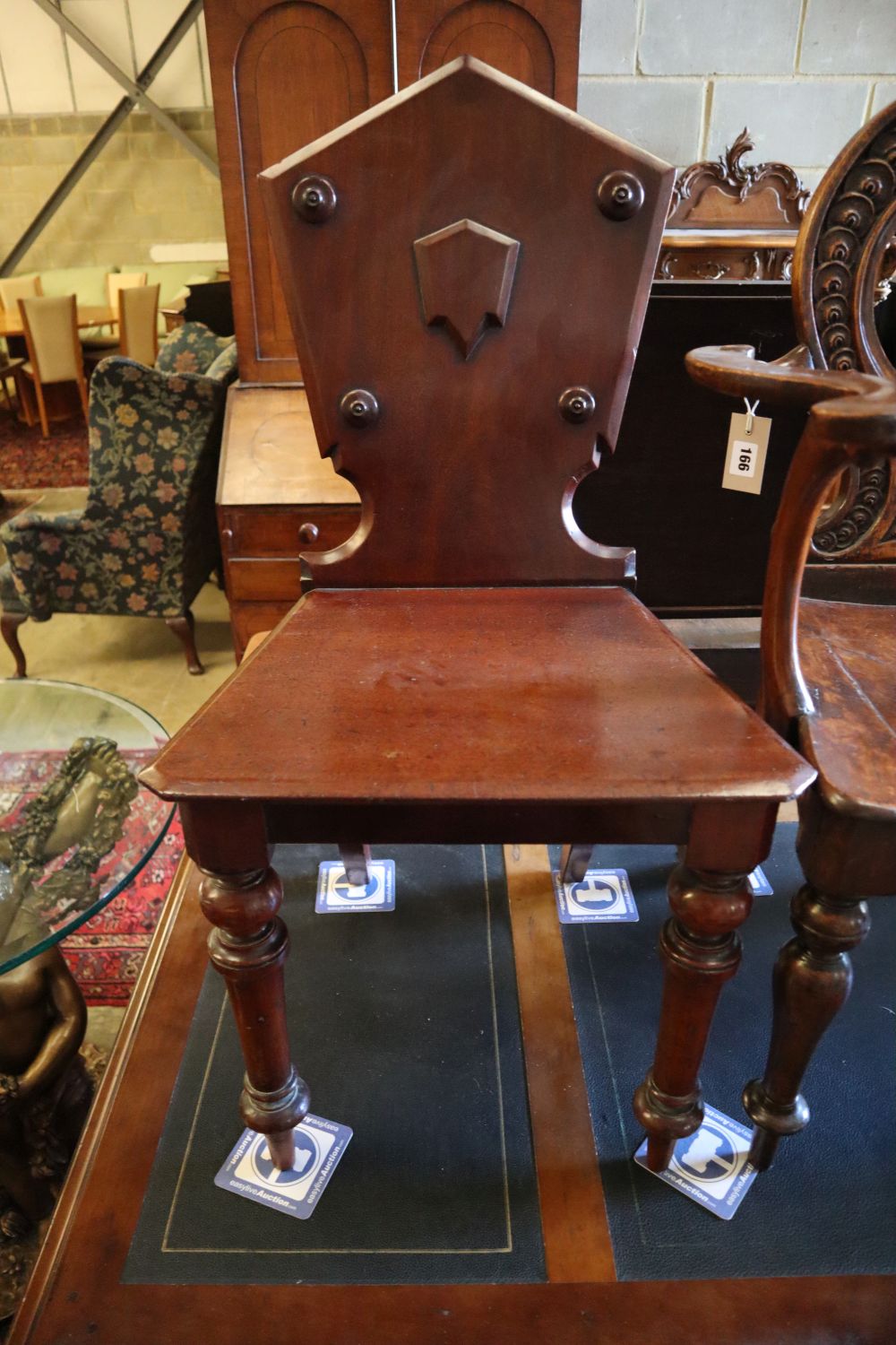 A 19th century carved oak hall elbow chair, together with two similar mahogany hall chairs